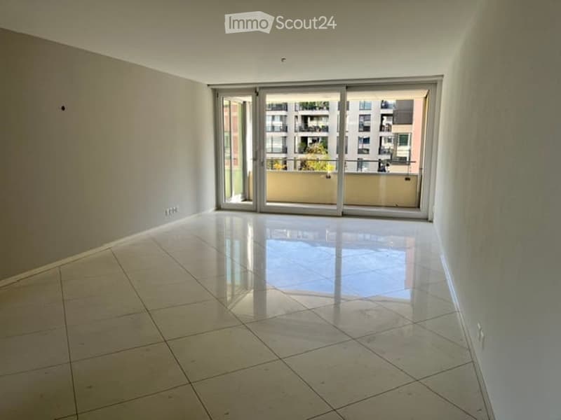 Empty room with tiled floor, large sliding glass doors leading to a balcony, and white walls.