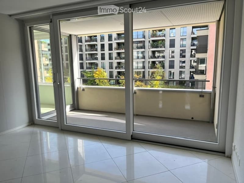 Empty room with large sliding glass doors leading to a balcony, white tiled floor, modern interior.