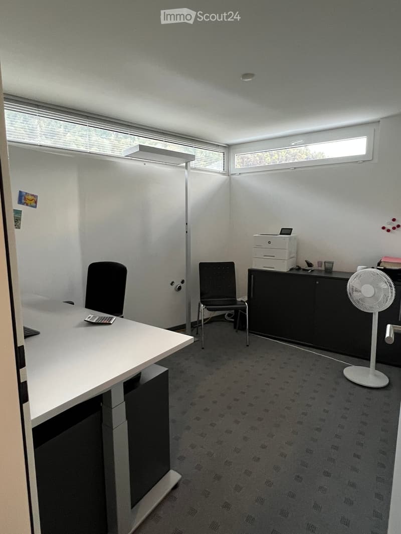 Office space with a white desk, two black chairs, a printer on a cabinet, a standing fan, and a calculator on the desk.