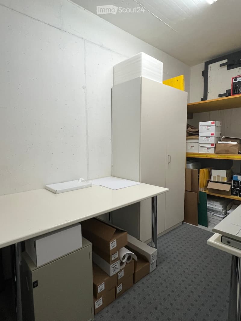 A small, organized room with a white table, a cabinet, and shelves holding boxes and files.