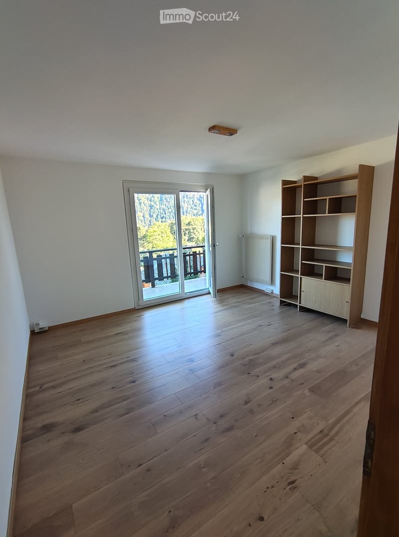 Empty room with wooden flooring, white walls, and a sliding glass door leading to a balcony.