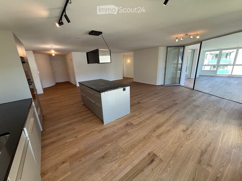 Empty room with wooden flooring, white walls, and large glass sliding doors leading to a balcony area.