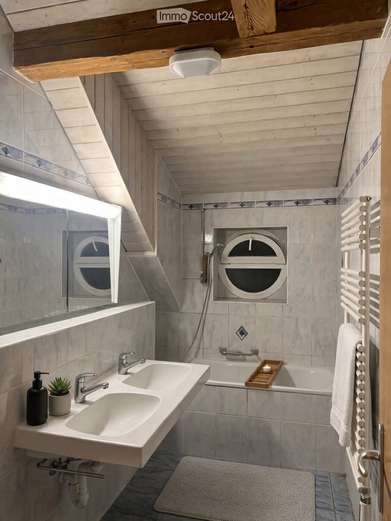 Modern bathroom with double sink, bathtub, towel rack, and decorative plant. Features wooden ceiling beams and large windows.