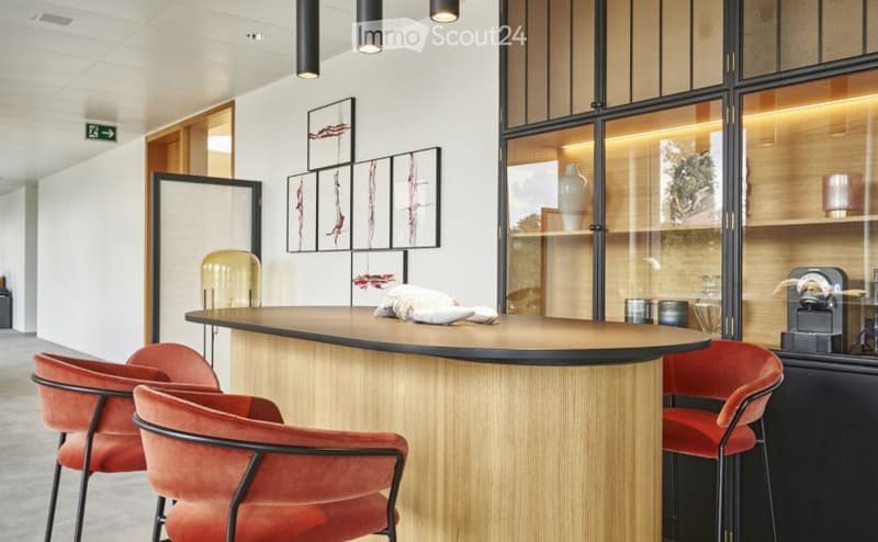 Modern reception area with a curved wooden counter, red chairs, and decorative vases on shelves behind glass panels.