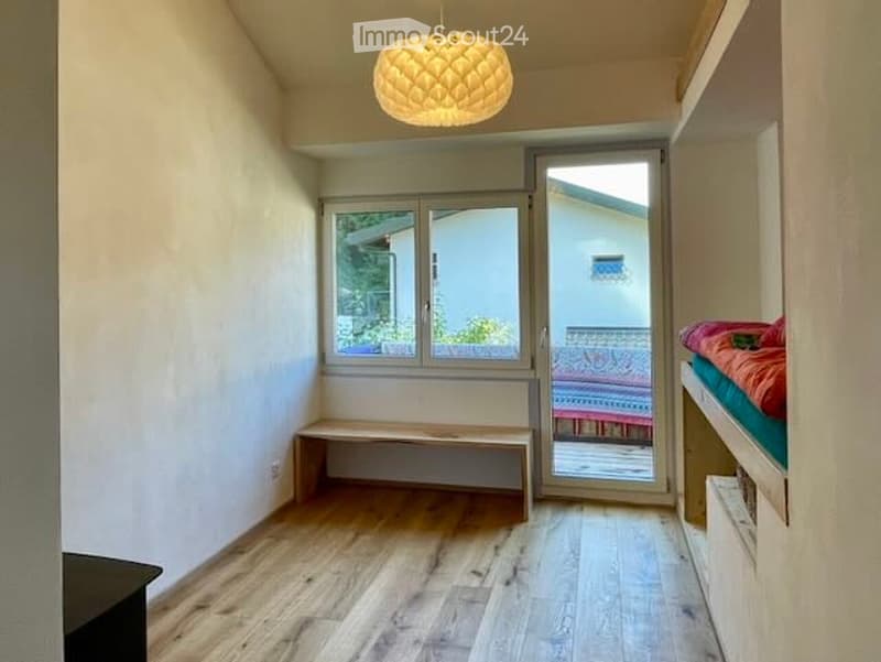 room with wooden floor, white walls, bench, glass doors to balcony