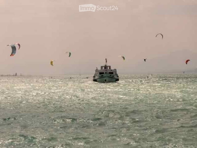 A boat sails on a body of water with several kites in the sky above, indicating a recreational or water sports setting.