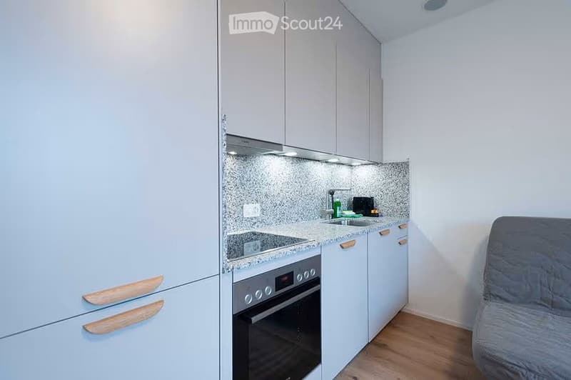 Modern kitchen with light blue cabinets, a built-in oven, a sink, and a countertop with a backsplash.
