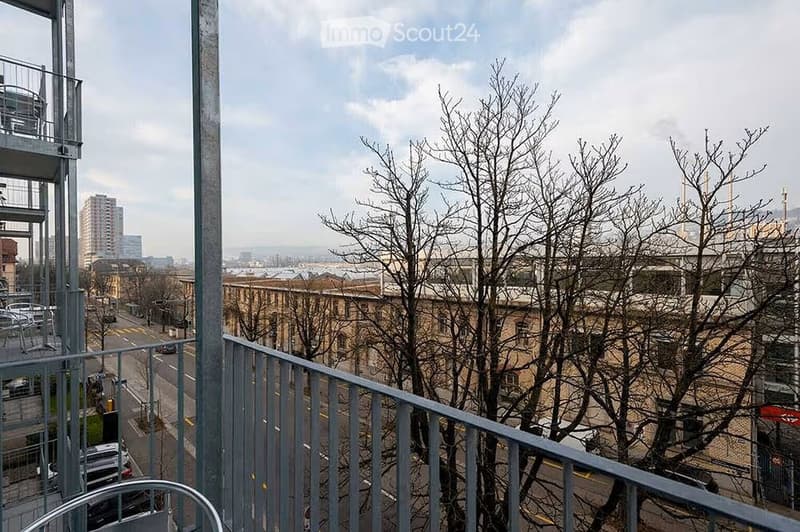 Balcony overlooking a cityscape with bare trees, buildings, and a road below.