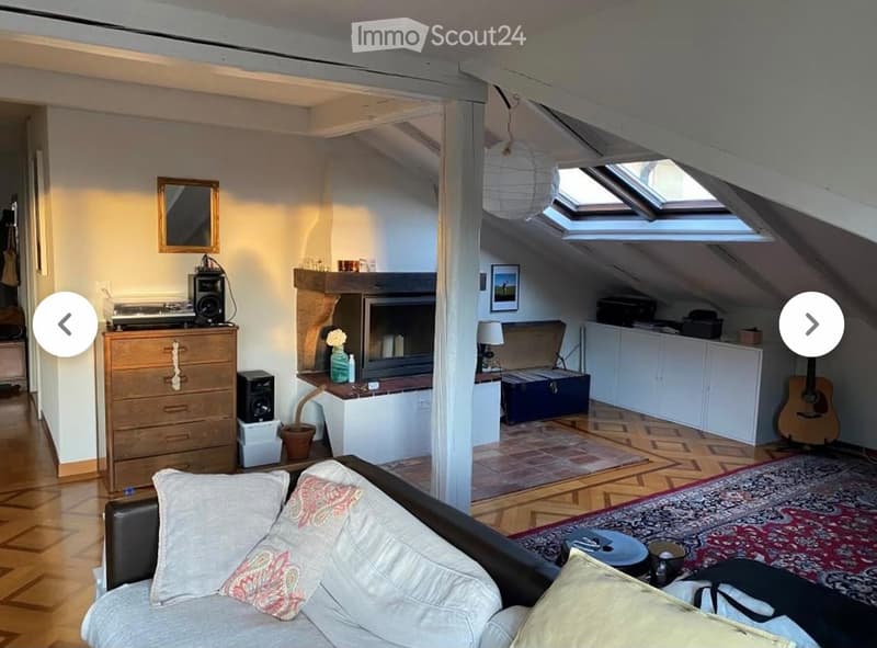A cozy attic living space with exposed wooden beams, a fireplace, a sofa, a guitar, and a cabinet.
