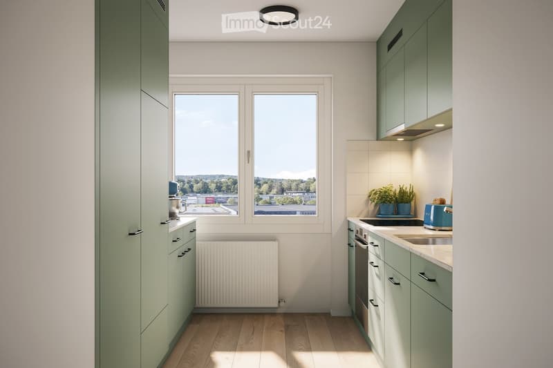 Modern kitchen with light green cabinets, wooden flooring, and large windows offering a view of greenery outside. Features include a sink, oven, toaster, and small potted plants on the counter.