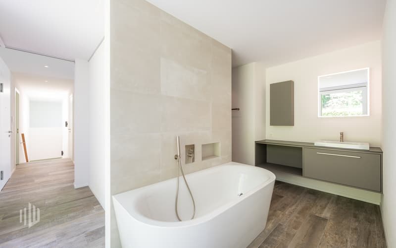 Badezimmer mit stilvoller Badewanne und dahinterliegender begehbarer Dusche