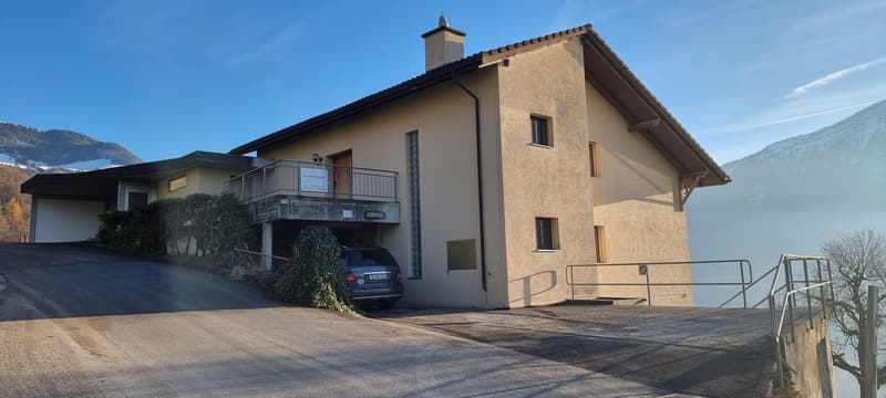two story house, tan wall, garage in basement, fenced balcony, mountain in background