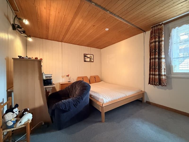 bedroom with bed, chair, desk, stuffed toys, picture frame, lamp, window with curtains