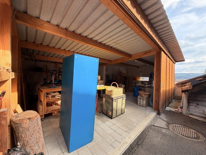 wooden structure, metal roof, wooden shelves, blue cabinet, wooden table, wicker basket, old trunk, tools, wooden logs