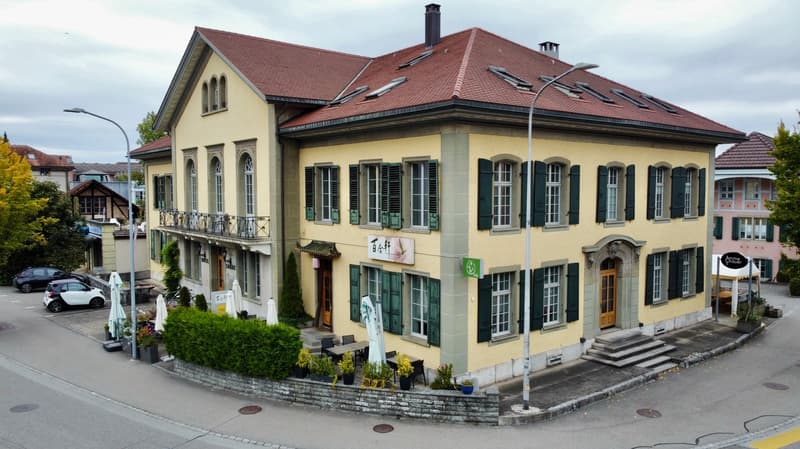 two story yellow building, red roof, green windows, yellow and green exterior, streetlight, balcony, garden, parking lot