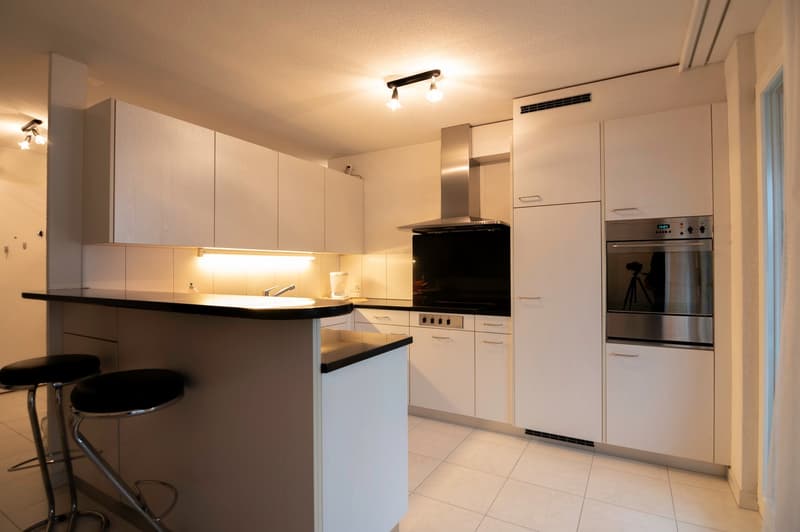 Modern kitchen with white cabinets, black countertops, and stainless steel appliances.