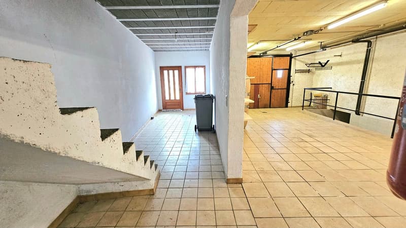 tiled floor, concrete wall, wooden staircase, two doors, trash bin