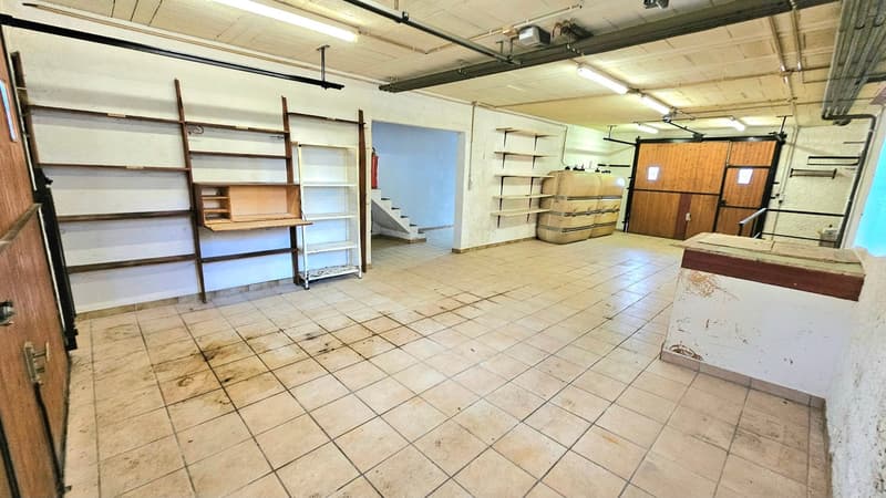 spacious room, tiled floor, metal shelves, open doors, light fittings, and a staircase with a railing in the distance