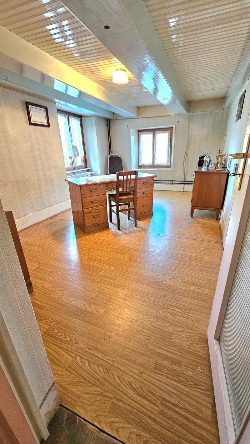 Wooden desk with drawers, wooden chair, picture frames, lamps, window sills with curtains, open door, ceiling lamp