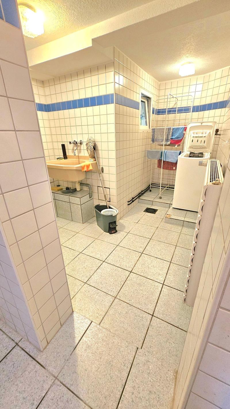 Tiled bathroom with sink, washing machine and dryer, and a drying rack