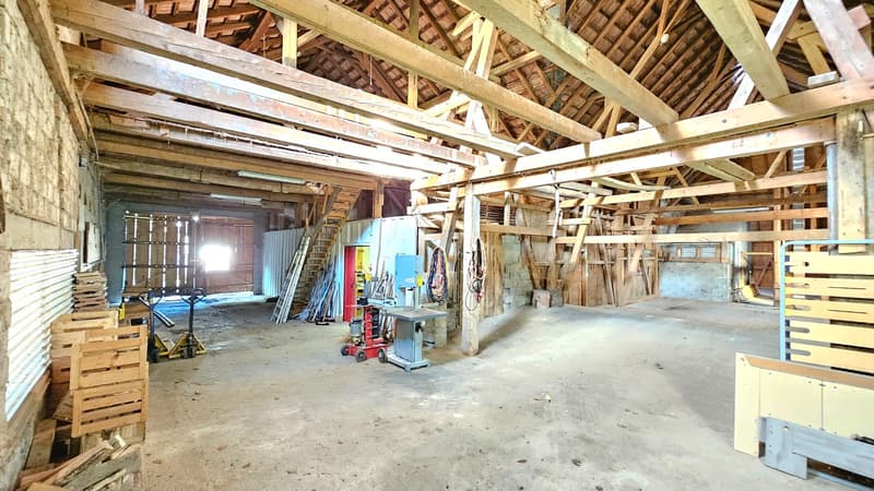 barn with high wooden ceiling, unfinished interior, wooden beams, stacks of wooden planks