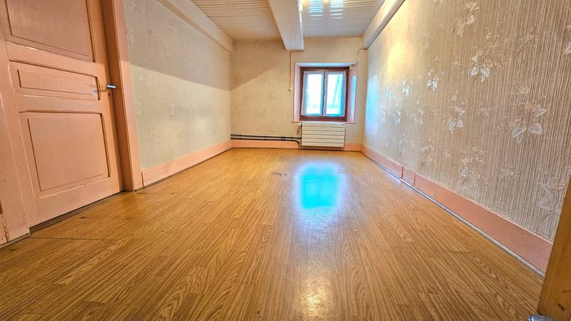 room with hardwood floors, walls with floral wallpaper, a window, and a door