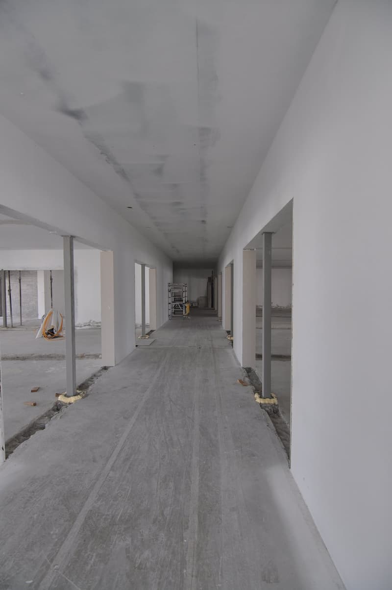 An empty corridor of an under construction building, concrete floor, walls, and pillars.