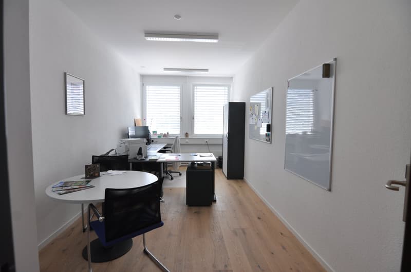 empty office with tables, chairs, computer, whiteboards, frames, wooden floor