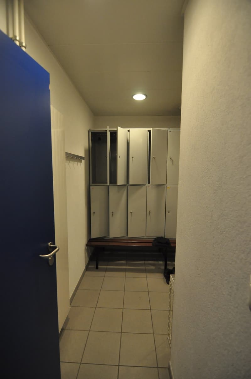 locker room with a door, a bench, and lockers