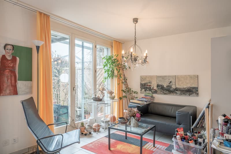 Living room: couch, coffee table, rug, glass door, chandelier, paintings, chair, lamp, potted plants, window