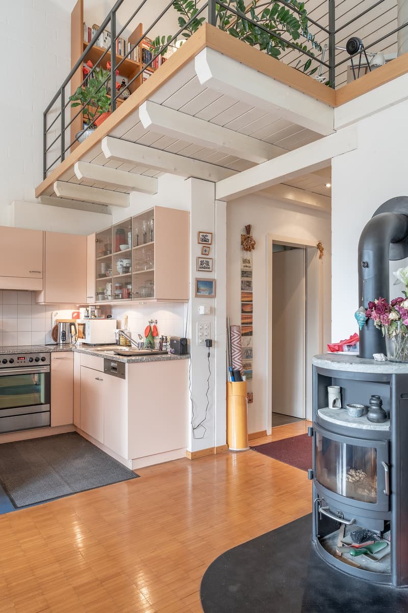 kitchen area, gas stove, cabinets, open mezzanine with bookcase, fireplace, wooden floor
