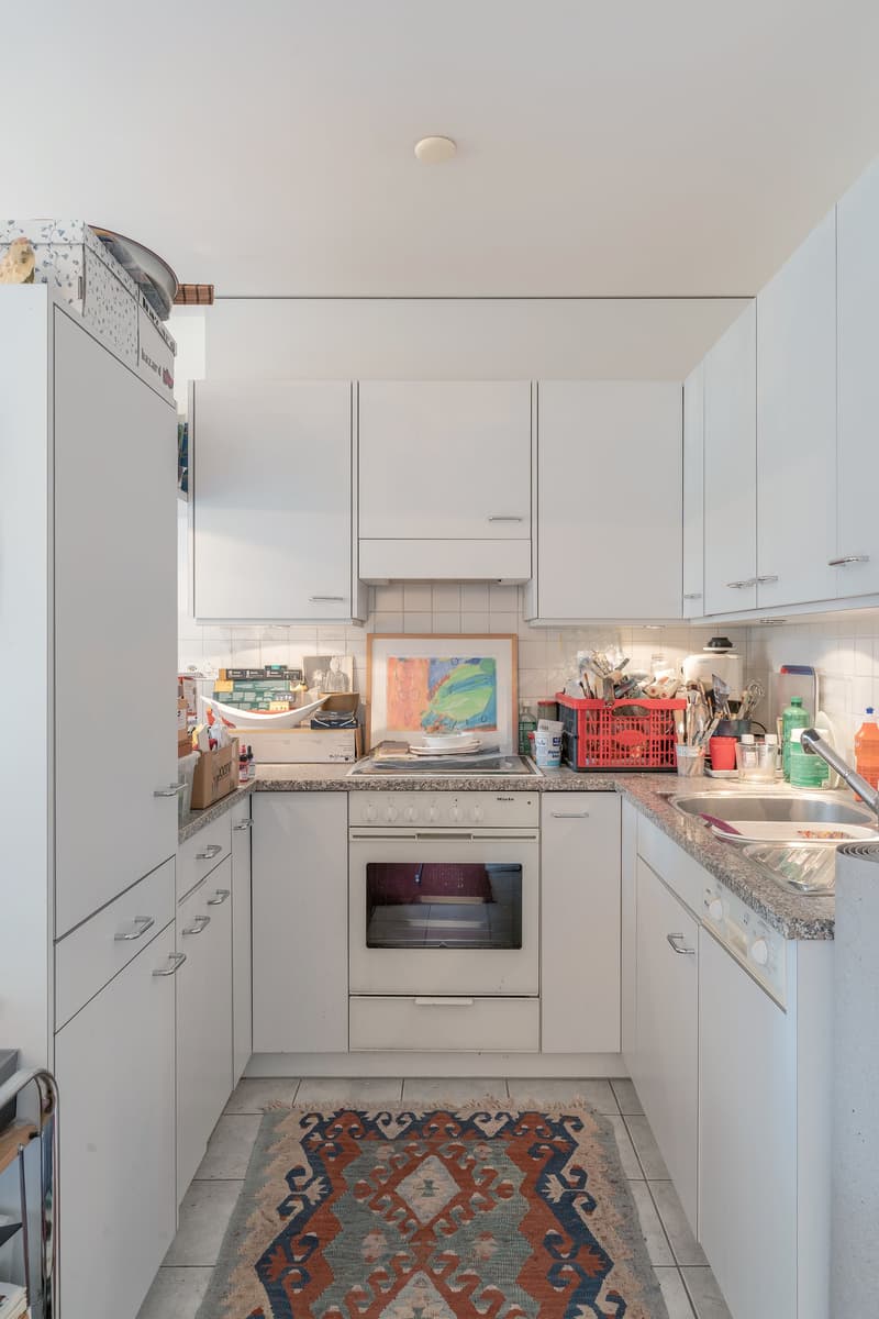fully equipped kitchen with white cabinets, granite countertop, sink, dishwasher, oven, refrigerator, rug, kitchen tools
