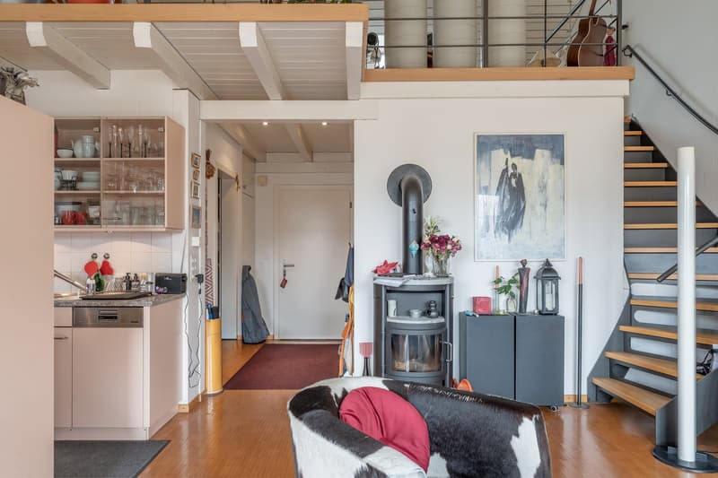 wood floor, open kitchen, living room with fireplace, cabinet with dishes, couch, stairs to upper floor