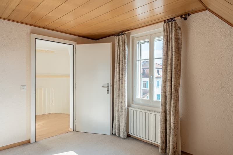 empty room, white door, wooden ceiling, white radiator, window with curtains