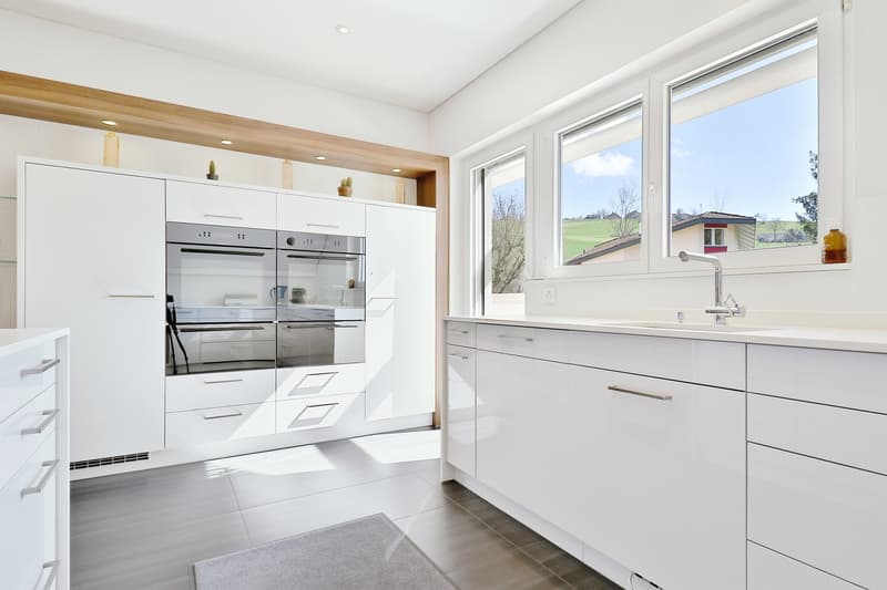 modern kitchen, all white, built-in oven and dishwasher, open windows, grey tiles, wooden shelves