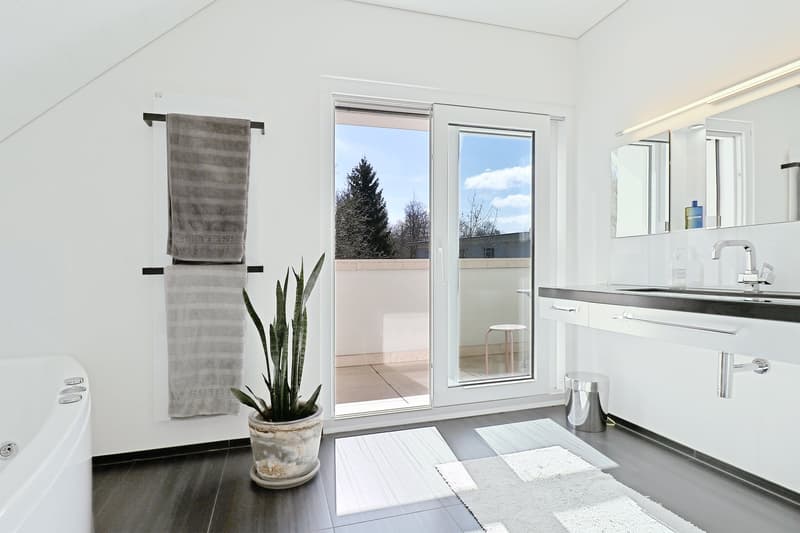 white tiles, bathtub, two towels, potted plant, modern faucet, mirror, balcony
