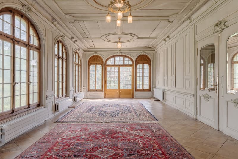 long hallway, wooden floors, large arched windows, wooden doors, chandeliers, radiators, carpets