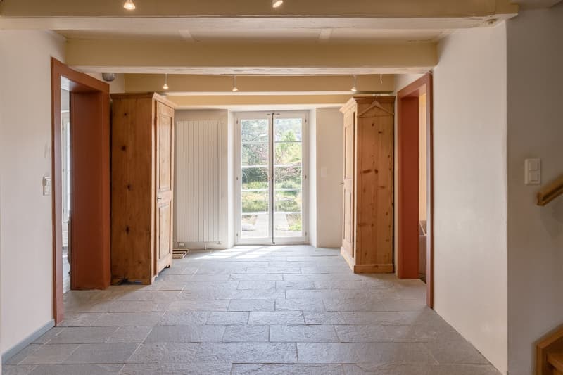 Empty hallway with wooden cabinets, sliding glass door, white walls, tiled floor, wooden ceiling