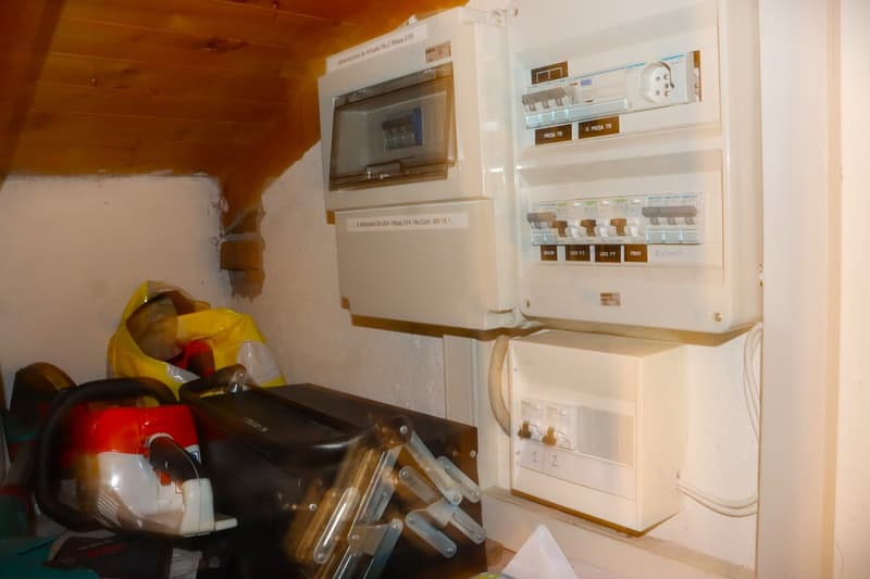 The image shows a utility room with a washing machine, dishwasher, and various household items and tools stored on the shelves.