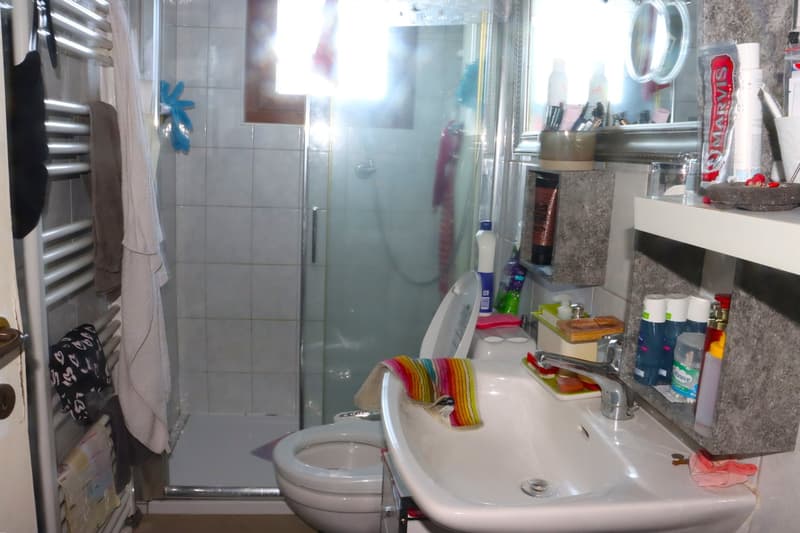 white tiles, shower, toilet, sink, mirror, shelves, various toiletries