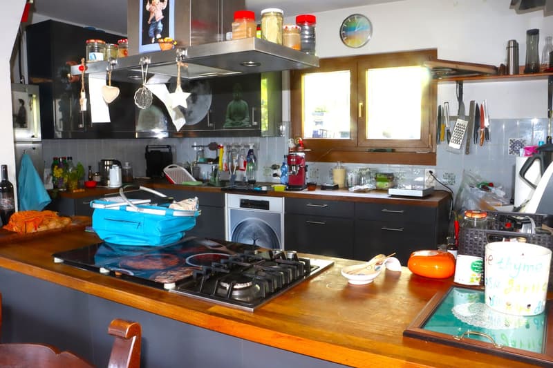 Central kitchen, wooden countertops, gas stove, wooden ceiling, large window