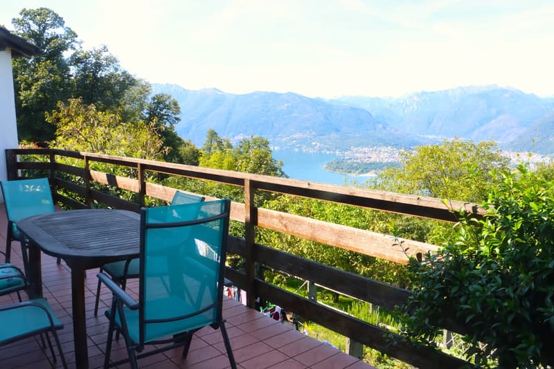 Table and chairs on a balcony with a view of the mountains and a lake