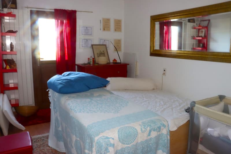 A single bed, blue and white cover, one pillow and one pillow cover, bedsheets, red couch, shelves, mirror, certificates on the wall, wooden box, radiator