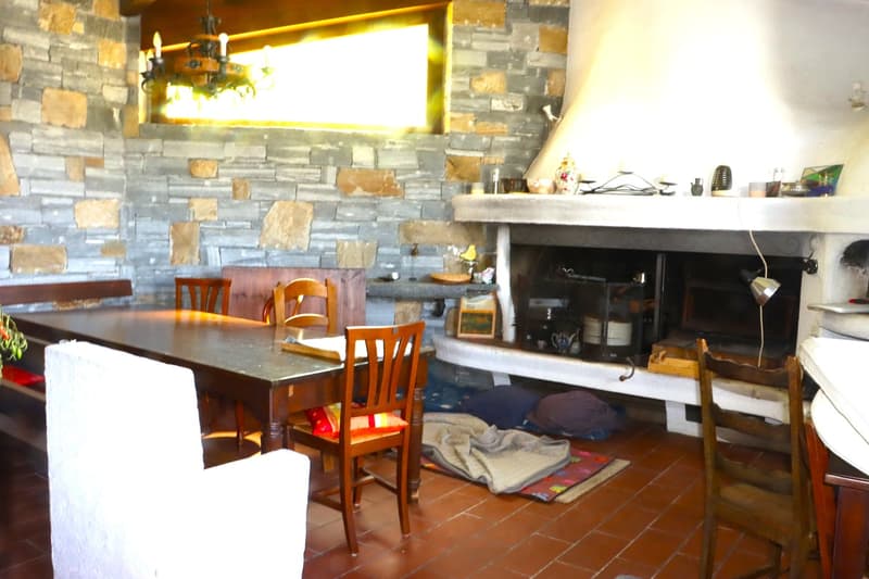 dining room with fireplace, stone wall, chandelier, dining table and chairs