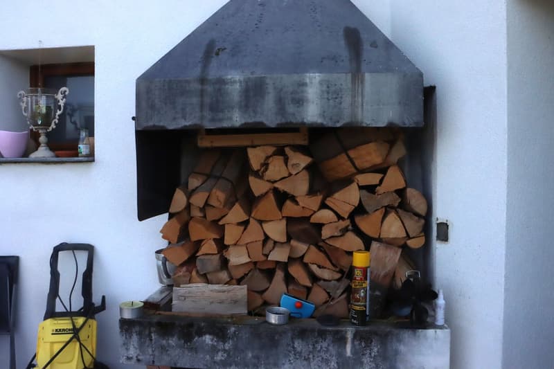 An outdoor fireplace with a stack of firewood and a trophy in the background