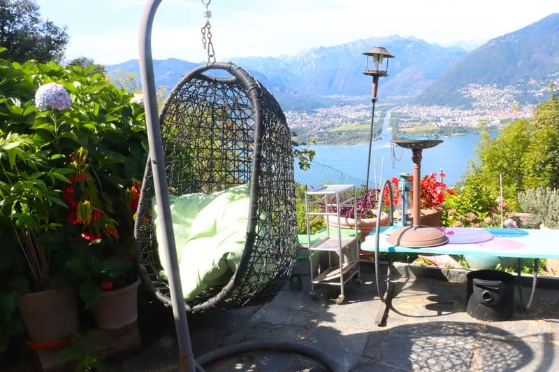 garden with view, hanging egg chair, table, lamp, potted plants, mountain landscape