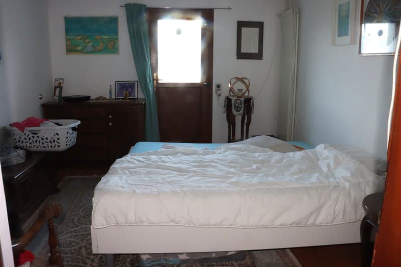 bed, rug, wooden chest, dresser, curtains, art frames, radiator