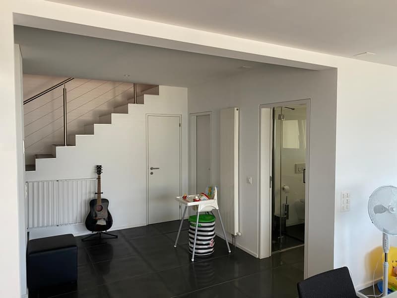 Interior space with staircase, black tile flooring, acoustic guitar, high chair, radiator, glass entrance