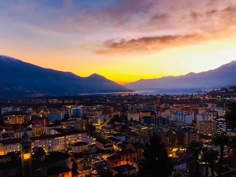A cityscape with mountains in the background, and a sunset over the mountains.