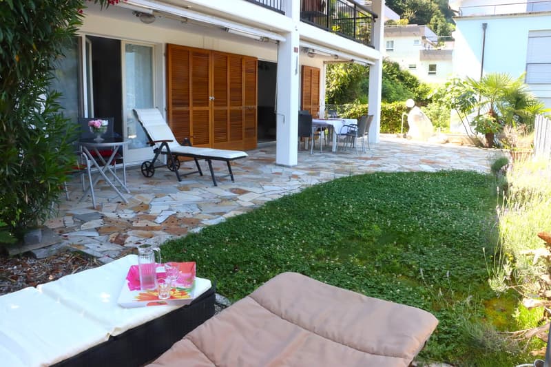 stone-paved patio with lounge chairs, outdoor dining set, flower vase, pitcher, magazines, cushioned lounger